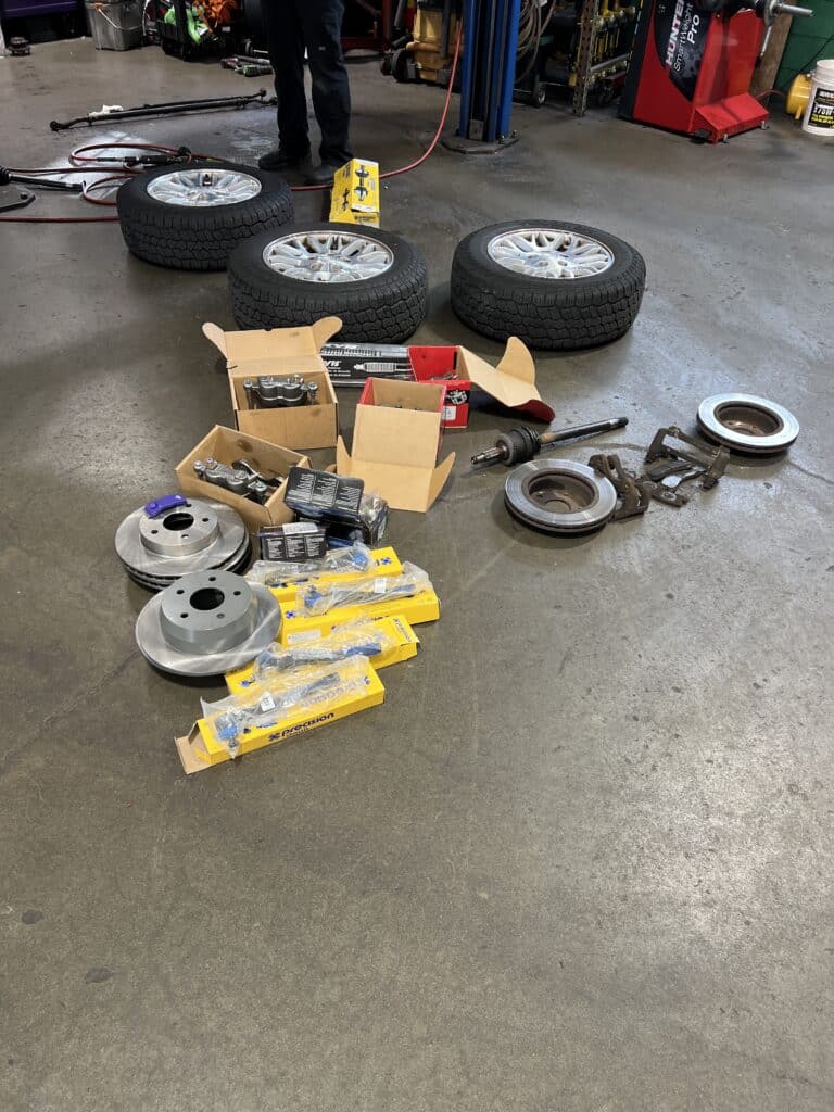 Brake, steering, axle and driveline parts laid out during repairs on a Jeep Grand Cherokee.