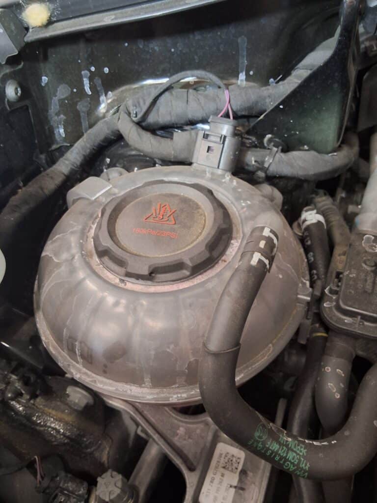 Dried coolant residue visible around the coolant reservoir on a 2021 Volkswagen Tiguan.