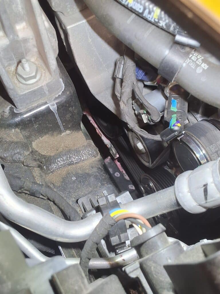 Dried pink coolant residue visible near the water pump and belt area of a 2021 Volkswagen Tiguan.