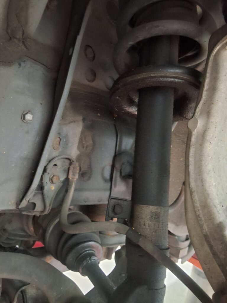 Leaking left front strut on a Lexus IS250 during suspension inspection.