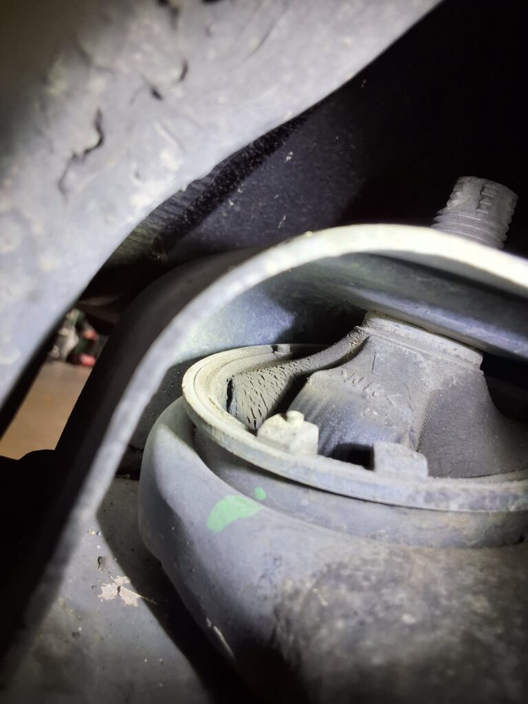 Cracking visible in a front control arm bushing on a Toyota Corolla during inspection.